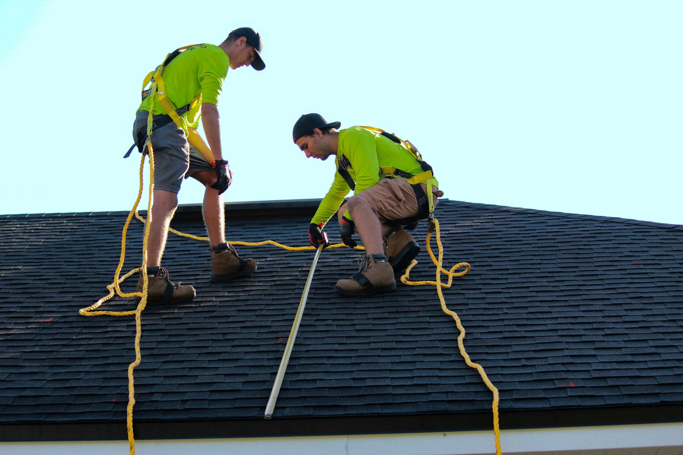 Roof professionals examining a shingle roof after storm damage